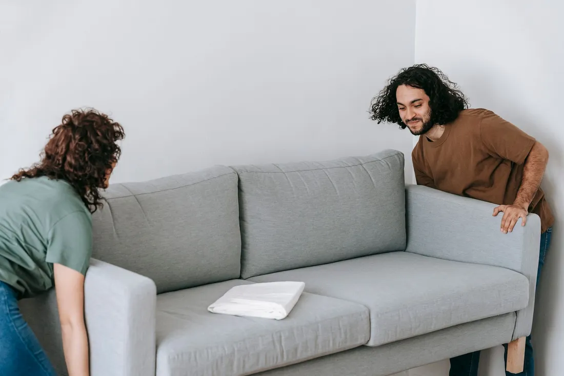 Zwei Helfer heben ein Sofa für den Transport an
