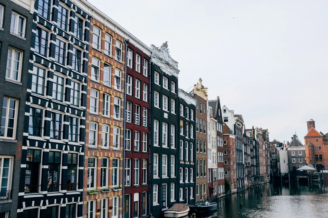Schmale Grachtenhäuser mit engen Treppenhäusern an einem Kanal in Amsterdam